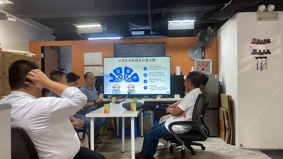 幾個人圍坐在桌旁,面向一幅顯示著簡報的屏幕。